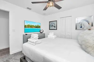 a white bedroom with a bed and a ceiling fan at Stunning 7BR Resort Pool Home 13 Min Disney in Kissimmee