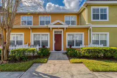 a yellow house with a red door and a white fence at Townhome Near Disney Mid Term rentals Welcome in Kissimmee