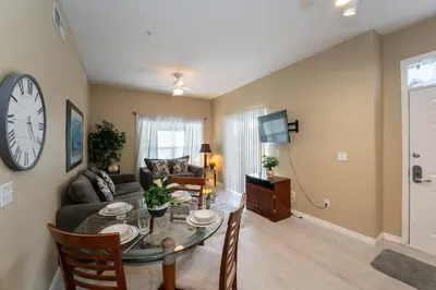 a living room with a table and a clock on the wall at Resort Bliss Near Disney Longer Stays Welcome in Kissimmee