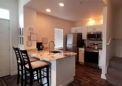 a kitchen with a counter with chairs and a counter top at Beautiful Townhome In a Resort Near Disney in Kissimmee