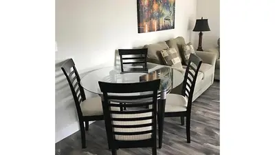 a glass dining room table with chairs and a couch at Beautiful Townhome In a Resort Near Disney in Kissimmee