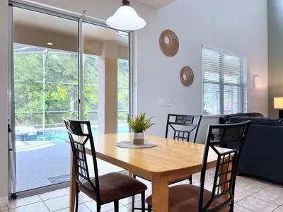 a dining room and living room with a wooden table and chairs at Disney Getaway Villa with Private Pool Hot Tub. Book Now VP140 in Kissimmee