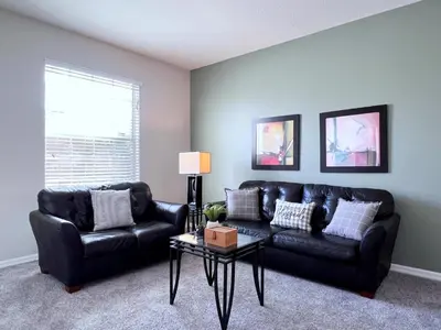 a living room with a black leather couch and a table at Disney Getaway Villa with Private Pool Hot Tub. Book Now VP140 in Kissimmee