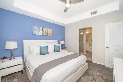 a bedroom with a large white bed with blue walls at Disney Getaway Luxury Condo with Private Balcony. Book Now SLR366 in Kissimmee