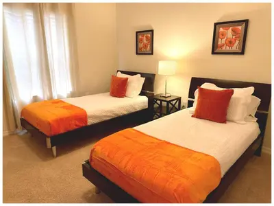 a bedroom with two beds with orange and white sheets at Disney Getaway Townhouse with Private Pool. Book Now SLR484 in Kissimmee