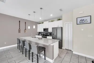 a kitchen with a large island with chairs and a refrigerator at Disney Getaway Private Pool Themed Bedrooms. Book Now SLR1162 in Kissimmee