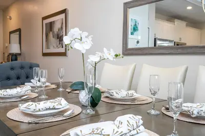 a table with plates and glasses and a vase with flowers at Disney Getaway Private Pool Themed Bedrooms. Book Now SLR410 in Kissimmee