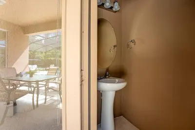 a bathroom with a sink and a mirror and a table at Disney Getaway Luxury Villa with Private Pool. Book Now BV75 in Kissimmee