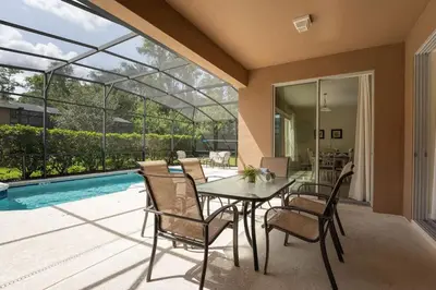 a dining room with a table and chairs and a pool at Disney Getaway Luxury Villa with Private Pool. Book Now BV75 in Kissimmee