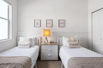 two beds in a white bedroom with a lamp on a night stand at Disney Getaway Private Pool Game Room. Book Now BV77 in Kissimmee