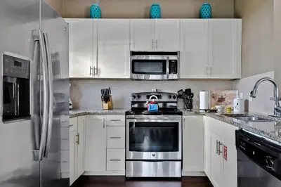 a kitchen with white cabinets and stainless steel appliances at Disney Getaway Private Pool Themed Bedrooms. Book Now LV7 in Kissimmee