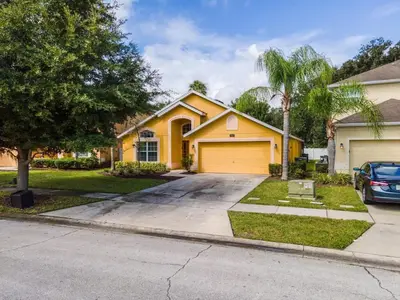 a yellow house with a driveway at Disney Getaway Luxury Villa with Private Pool Game Room. Book Now VP48 in Kissimmee