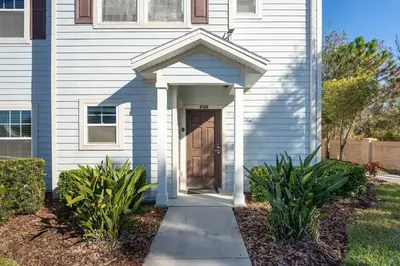 a white house with a door and some plants at Disney Getaway Private Pool Themed Bedrooms. Book Now WLV19 in Kissimmee