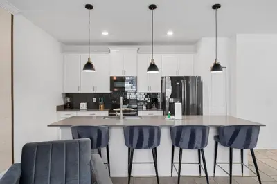 a kitchen with a large island with blue bar stools at Disney Getaway Private Pool Themed Bedrooms. Book Now SLR370 in Kissimmee