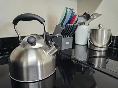 a tea kettle is sitting on a stove with utensils at 2BR 2BA Grand Duo Suite Sleeps 8 Near Universal and I Drive in Orlando