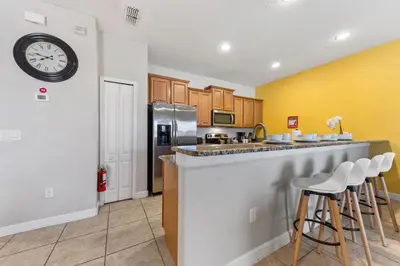 a kitchen with a bar with stools and a clock on the wall at 8847 Candy Palm Rd in Kissimmee