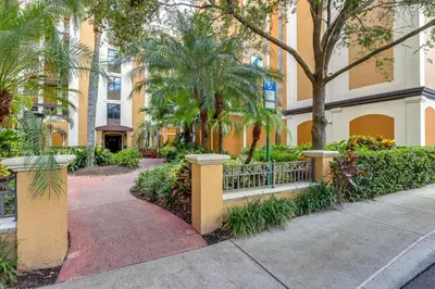 a building with a fence and trees and a sidewalk at Poolside Oasis 7 Mi to Disney and Universal in Orlando