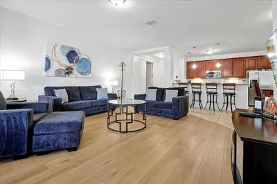 a living room with blue couches and a kitchen at Epic Universe Beautiful Modern Condo-Vista Cay-2026 in Orlando