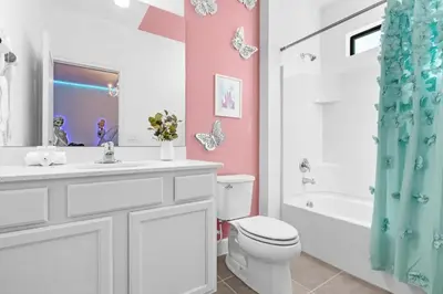 a bathroom with a white toilet and a pink wall at Epic Paradiso Mansion-Pool,Game Room,Theater-4 in Orlando