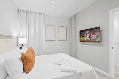 a white bedroom with a bed and a tv on the wall at Casa Luxo 5 Suítes | Perto da Epic Universe in Orlando