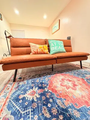an orange couch with pillows on top of a rug at Modern Studio with Exterior Independent Entrance in Orlando