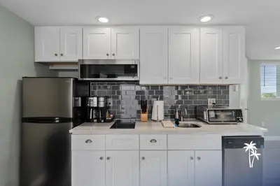 a kitchen with white cabinets and a stainless steel refrigerator at Lake View Top Floor 2 Bed 2 Bath Condo with Balcony in Orlando