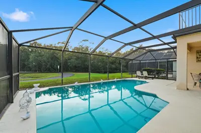 a swimming pool in a glass house with a patio at Near Disney Pool Hot Tub Stunning Water View in Kissimmee