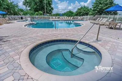a large swimming pool with chairs and an umbrella at Skyline Studio Condo with Private Terrace and Epic Universe View in Orlando