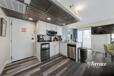 a kitchen with white cabinets and a refrigerator at Skyline Studio Condo with Private Terrace and Epic Universe View in Orlando