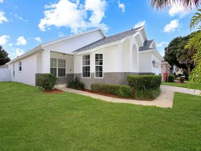 a white house with a green yard at Castle Keys Salt Water Pool Home 10 mins to Disney in Kissimmee