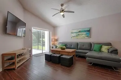 a living room with a couch and a ceiling fan at Poolside Vacation Home in Kissimmee Near Disney in Kissimmee