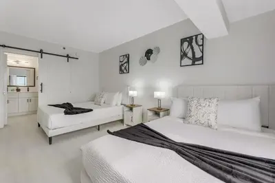 a white bedroom with two beds and two tables at Luxury Private Apt at Disney Area in Orlando