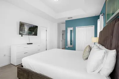 a bedroom with a white bed and a blue wall at Upstay - Resort Home w Cinema Pool & Lake View in Kissimmee