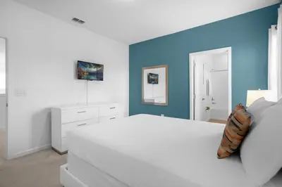 a bedroom with a white bed and a blue wall at Upstay - Resort Home w Cinema Pool & Lake View in Kissimmee