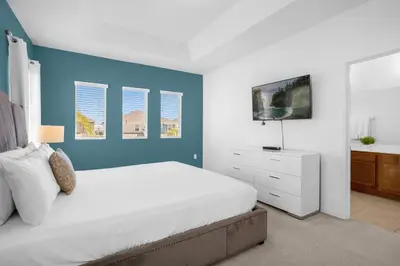 a bedroom with a white bed and a blue wall at Upstay - Resort Home w Cinema Pool & Lake View in Kissimmee
