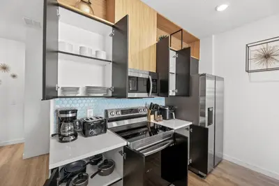 a kitchen with stainless steel appliances and wooden cabinets at Modern Townhome 10min to Disney in Kissimmee