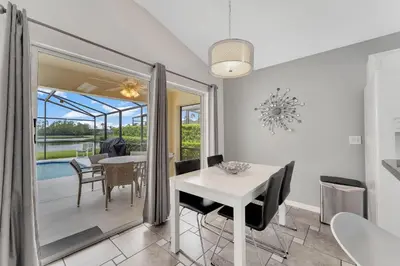 a dining room with a white table and chairs and a patio at Casa Vista Lago c/ Piscina Privada – Próx. Disney in Kissimmee