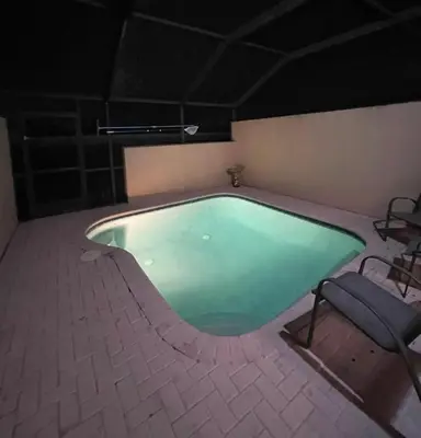 a large swimming pool with a chair and a table at Relaxing vacation resort villa in Orlando