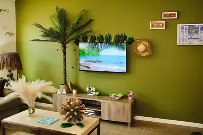 a living room with a tv on a green wall at Margaritaville House Close to Universal in Kissimmee