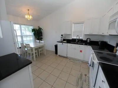 a kitchen with white cabinets and a table in it at Holiday Hideout by Paradise Resort Vacations in Orlando