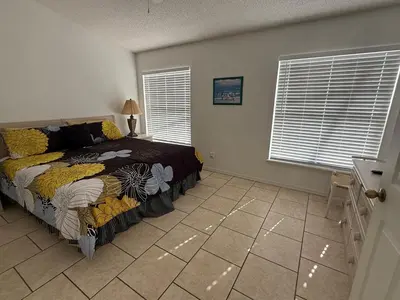 a bedroom with a bed and two windows and a tiled floor at Holiday Hideout by Paradise Resort Vacations in Orlando