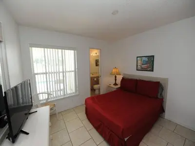 a bedroom with a red bed and a television at Holiday Hideout by Paradise Resort Vacations in Orlando