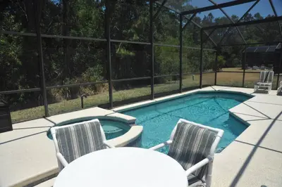 a swimming pool with two chairs and a table at Sunshine Serenity by Paradise Resort Vacations in Kissimmee