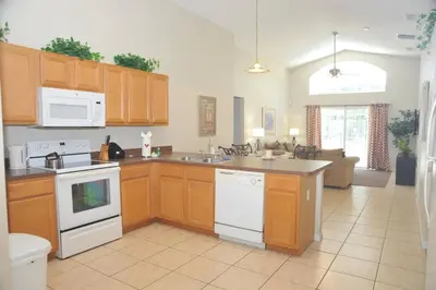 a kitchen with wooden cabinets and white appliances at Sunshine Serenity by Paradise Resort Vacations in Kissimmee