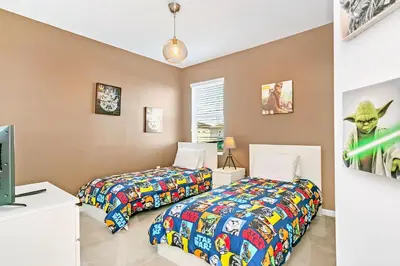 two beds in a room next to a tv at UPSTAY- 10BR Mansion wPrivate Pool and Games Room in Kissimmee