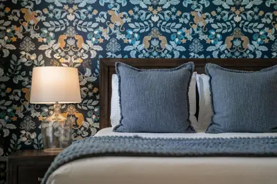 a bedroom with a bed with a lamp and wallpaper at Tiki Palms Play and Pool Near Disney in Kissimmee