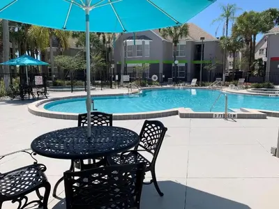 a table and chairs with an umbrella in front of a pool at Two bed condo in Parkway Palms Resort in Orlando
