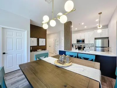 a kitchen and dining room with a wooden table and blue chairs at Beautiful Three bed condo, Minutes from Disney in Kissimmee