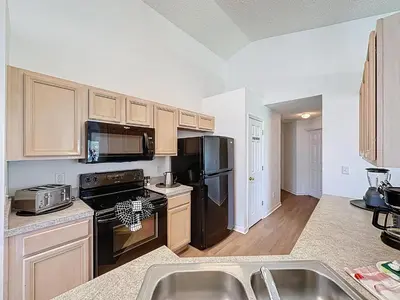 a kitchen with black appliances and wooden cabinets at Emerald Island 4Bd/3Ba Villa, 3 miles to Disney in Kissimmee