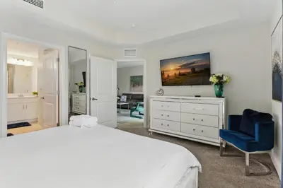 a white bedroom with a bed and a blue chair at Storey Lake condos by Une Homes in Kissimmee